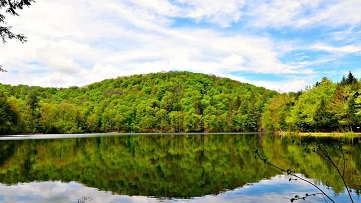 Photo of lake with a tree-covered hill in the background in Vermont