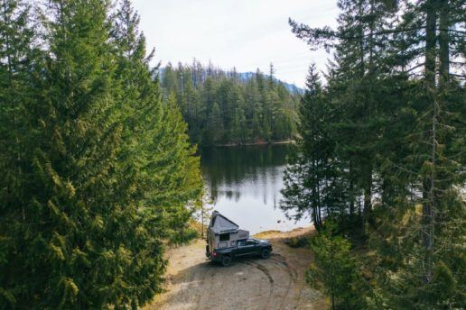 A photo of a Scout brand truck camper near a lake